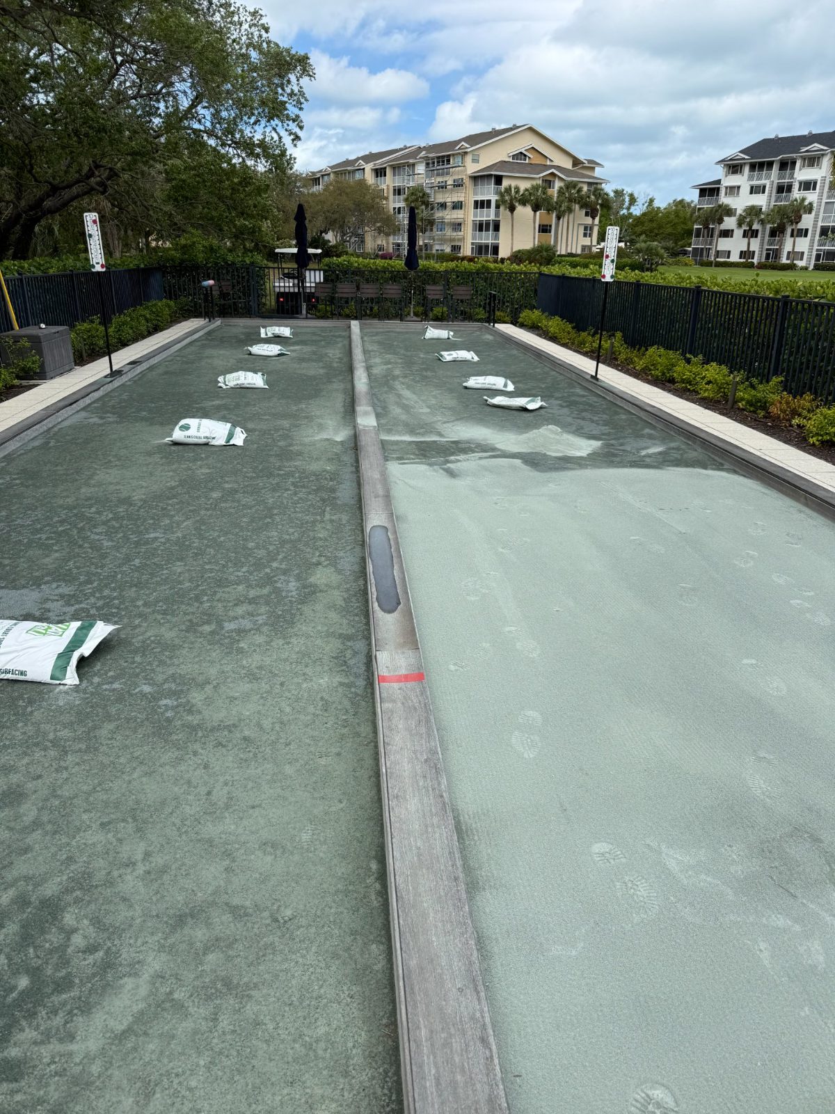 Bocce ball court with white pallinos on green playing surface in residential community